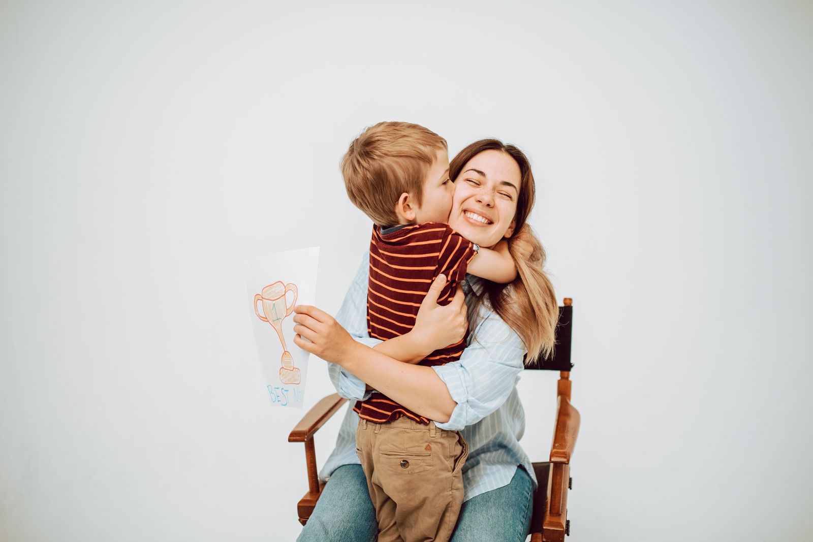 A parent sitting with a young child held close, in soft daylight.